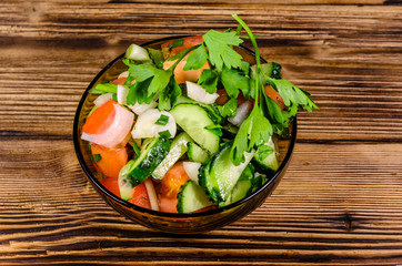 Salad with cucumbers and tomatoes on wooden table