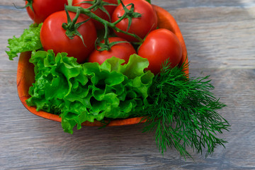 Green onions, tomatoes, dill lying on a wooden plate. salad ingredients, top view, copy space, rustic style. Vegetarian organic self grown food, health or cooking concept.