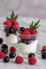 Delicate yogurt in glasses with raspberry and currant berries.