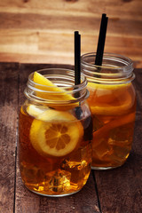 Iced tea with lemon slices and mint on rustic background