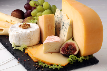 Cheese platter with different cheese, fig, salad and grapes