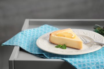 Ceramic plate with delicious cheesecake and fork on blue napkin