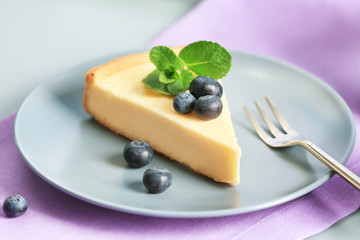 Plate with cheesecake, berries and fork on violet napkin