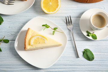 Plate with delicious cheesecake, fork and cup of coffee on wooden table