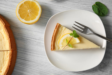 Plate with delicious cheesecake and fork on wooden table