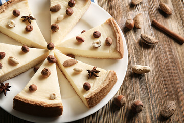 Delicious sliced cheesecake with nuts on wooden table