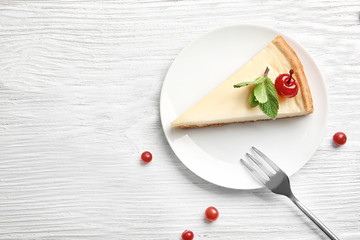 Plate with delicious cheesecake and cherry on white table
