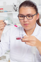 A teenage girl in a school laboratory in chemistry , doing experiments in lab.
