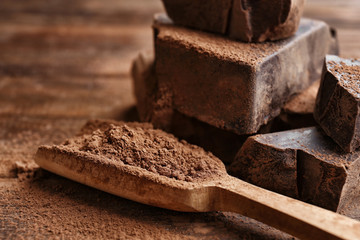 Wooden scoop with cocoa powder and chopped chocolate chunks, closeup