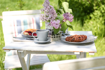 Beautiful table setting for dinner outdoors with lilac flowers