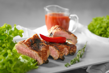Delicious grilled sliced spare ribs with salad leaves and pepper on white plate