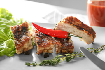 Delicious grilled sliced spare ribs with salad leaves and pepper on white plate