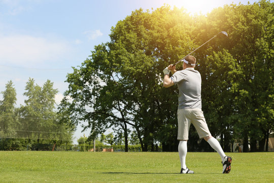 Young man playing golf on course in sunny day