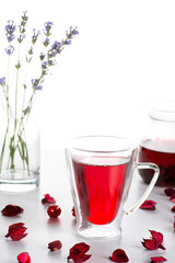 The cup with double glass with hibiscus tea is on a table.