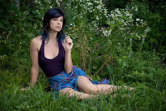 Woman In Skirt And Halter Top Sitting In Grass