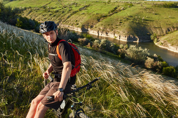 Mountain bike adventur. Cyclist has a rest on riverside.