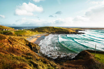 Beautiful Irish bay in Donegal with turquoise water and big waves clashing against the beach of a...