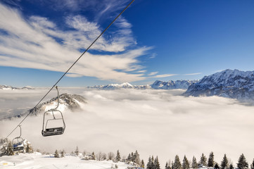Stunning shot of a ski slope and a chair lift near the Bavarian town of Garmisch Partenkirchen near Zugspitze mountain in Germany. Beautiful snow-covered trees and mountain ranges in the background.