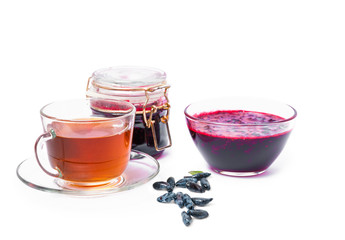 Jam with honeysuckle, blue honeysuckle berries and tea in a glas