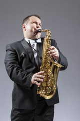 Fototapeta na wymiar Music and Musicians Ideas and Concepts. Portrait of Caucasian Mature Expressive Saxophone Player Playing the Instrument Against White Background.