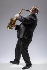 Naklejka premium Music Concepts. Full Length Portrait of Caucasian Mature Concentrated Saxophone Player Playing the Instrument Against White Background.