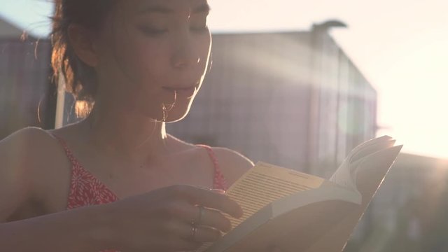 girl reading book at park in summer sunset light.