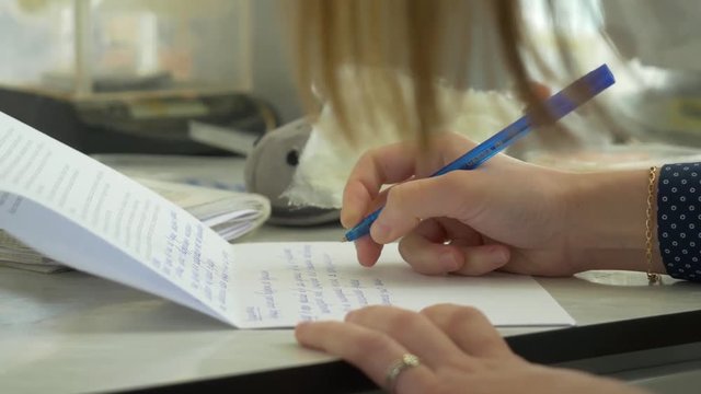 Closeup of a female hand writing on an blank notebook with a pen. Close-up of a female hand writing on an blank notebook with a pen