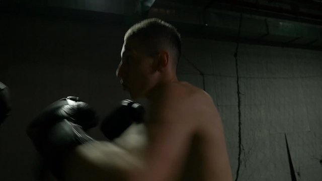 Slow motion of boxer training uppercut punches in boxing gym with pugilist trainer