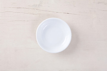 Top view of empty white plate put on white wood table with space for copy.
