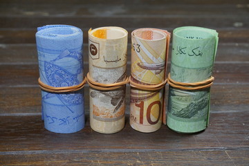 Malaysian Ringgit (MYR) roll tied with a rubber band on a wooden background.