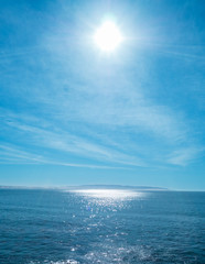bright sun in blue sky with clouds over the sea