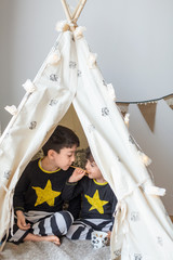 Brothers playing in a teepee