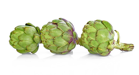 Obraz premium Three fresh artichokes with stem and leaf and a half showing the heart. Isolated.