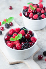 Close up of Summer fresh berries in white bowl on gray concrete table background. Vegetarian food - raspberry, blackberry and cherry
