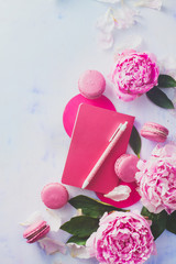 Minimal styled flat lay with peony flowers with petals, stationery and notebooks on a pastel background