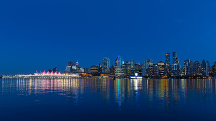 Fototapeta na wymiar A view on Vancouver city skyline from Stanley Park at night, Canada. Urban downtown panorama with Canada Place colorful sails along the coastal harbor line.