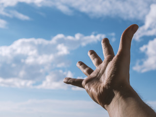 Hand of a man reaching to towards sky. Color toned image. Selective focus.