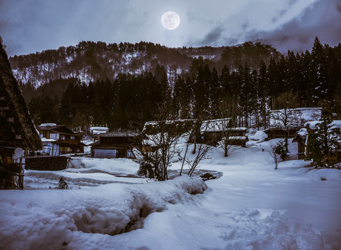 Snow covered ground in winter. Town with night sky and full moon, serenity nature.