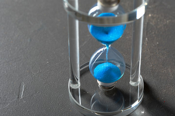 Time is passing. Blue hourglass close up