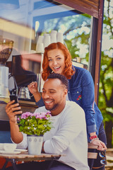 Redhead female and Black smiles male using smartphone.