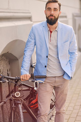 Fototapeta na wymiar Portrait of elegant bearded guy near the retro bicycle.