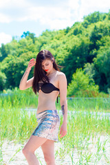 Naklejka na ściany i meble Young beautiful woman rest on a nature outdoors in glitter skirt and swimwear. Good mood and having fun on a sunny day