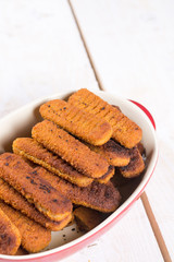 Fried fish meat sticks in the bowl above wooden table