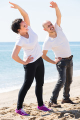  man and woman exercising together on the beach