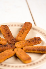 Fried fish meat sticks on the plate above wooden planks  table