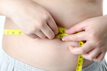 The boy with his belly with a tape measure on a white background, concept fat boy, unhealthy.