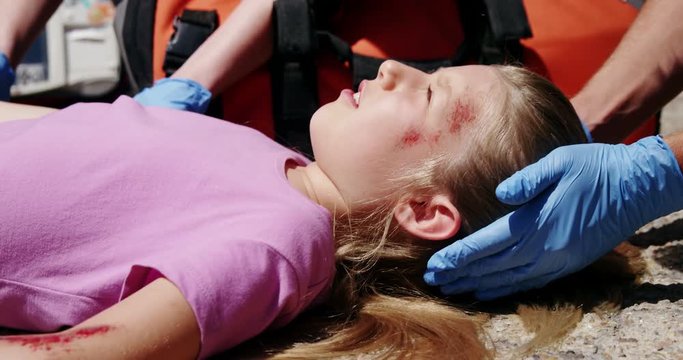 Paramedics examining injured girl