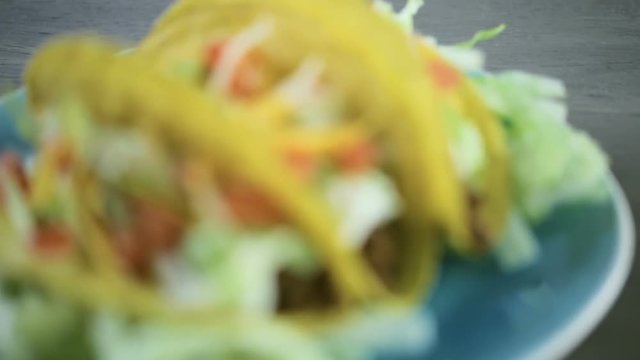Close up of fresh beef tacos in hard yellow corn taco shell with sour cream and shredded cheese