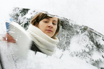 Eine Frau kratzt Eis von der Windschutzscheibe 