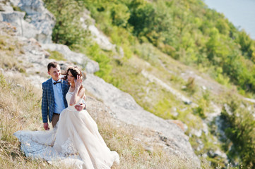 Beautiful wedding couple walking and enjoying each other's company in a rocky district with tall dry grass.